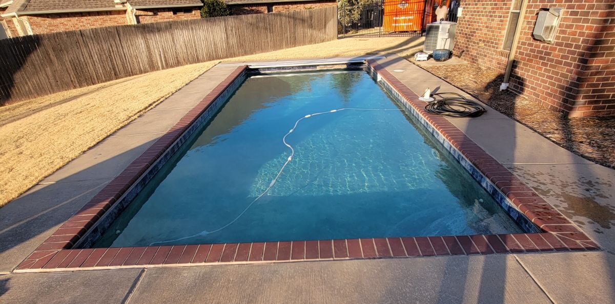 Before image of an outdated geometric pool with brick coping and old waterline tile.